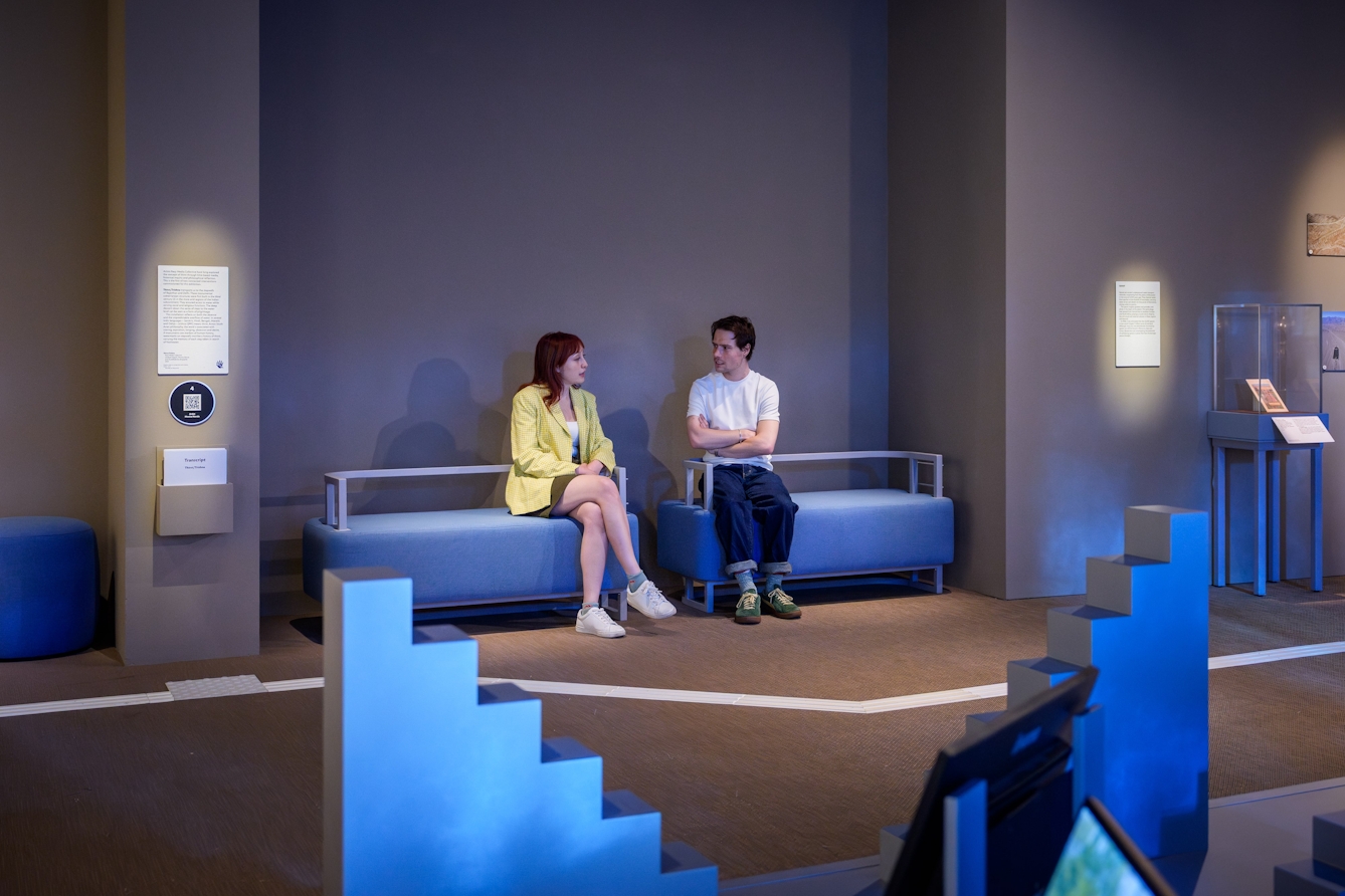 Two people sitting on some benches having a conversation.