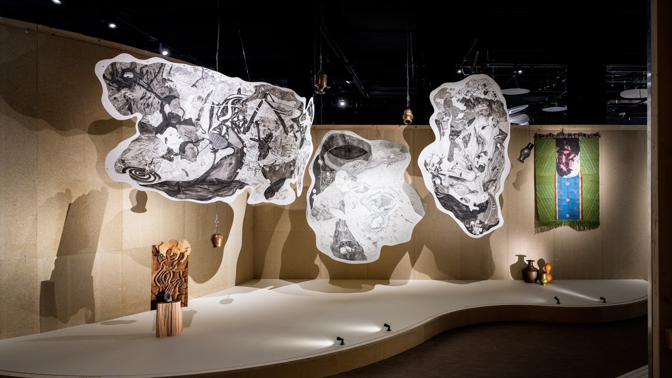 Three hanging ink drawings on cotton paper, suspended from the ceiling.