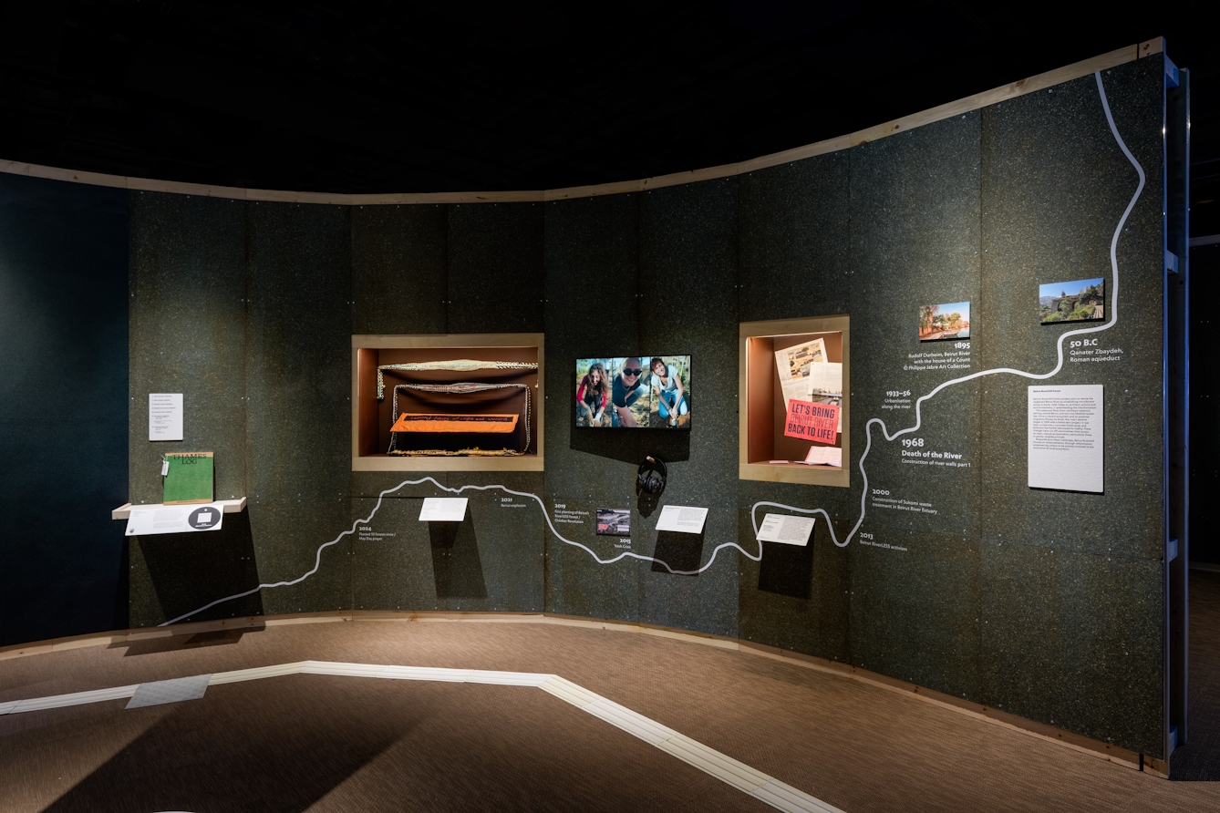 A display about the Beirut RiverLESS Forest featuring pamphlets, newspaper articles, woven prayer belts and a film.