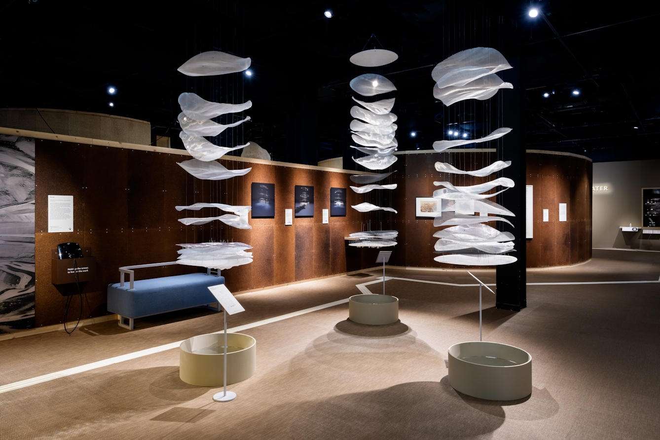 Three large sculptures suspended from the ceiling that show the different layers of water below the ground.