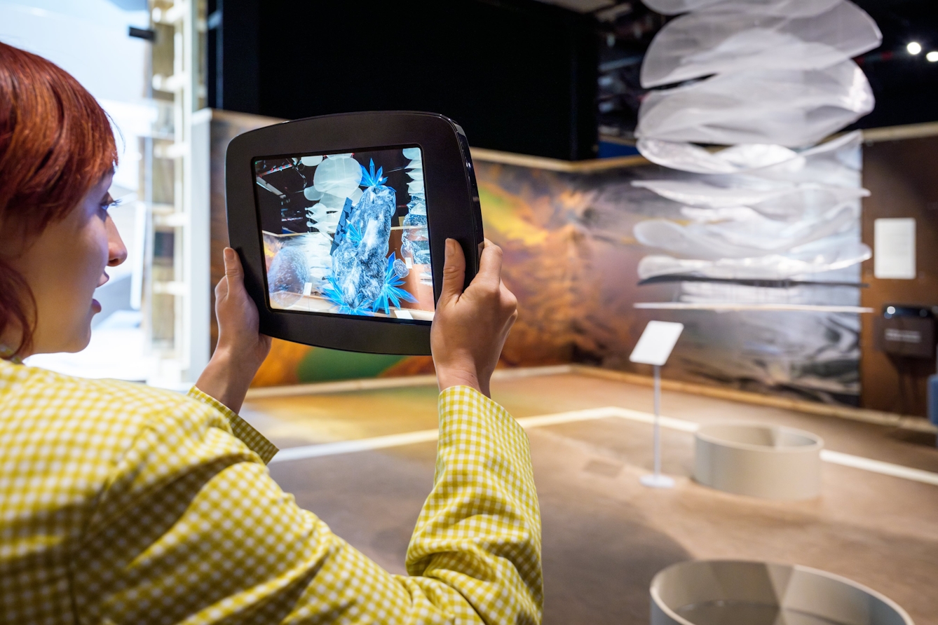 Person holding up an iPad and viewing augmented reality, water-rich asteroids on the screen.
