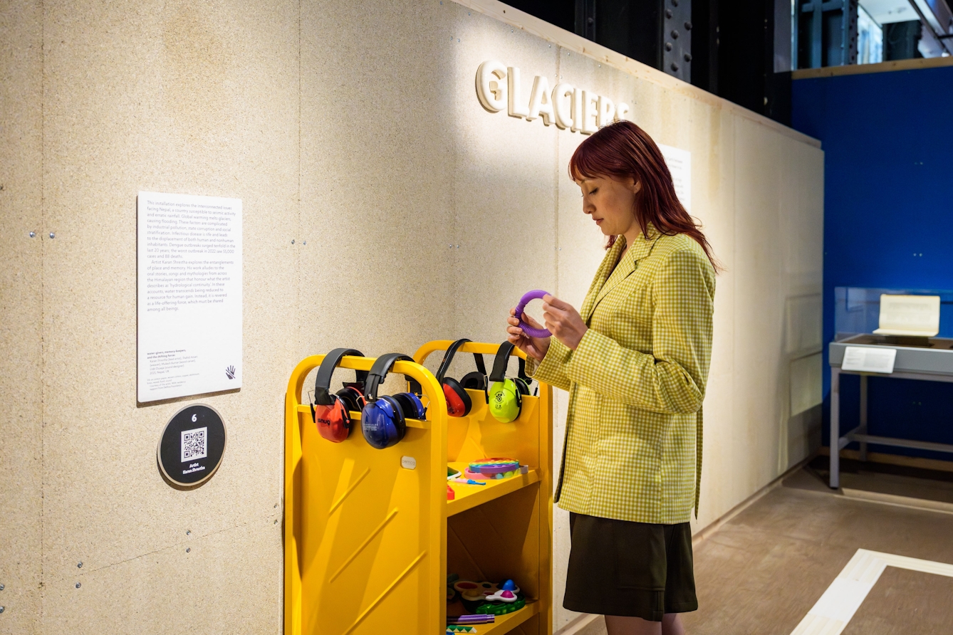 Person standing by some shelves that house ear defenders and fidget toys.