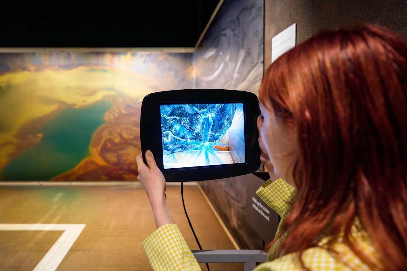 Person holding up an iPad and viewing augmented reality, water-rich asteroids on the screen.