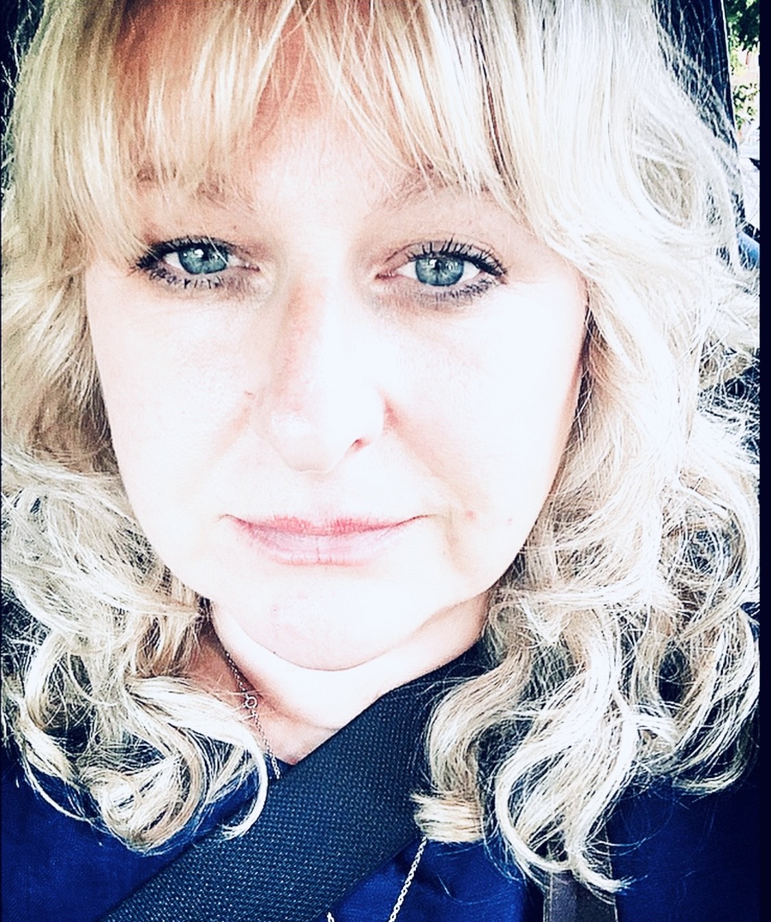 Head shot of a woman with shoulder-length, curly hair who is smiling directly to camera.