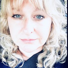 Head shot of a woman with shoulder-length, curly hair who is smiling directly to camera.