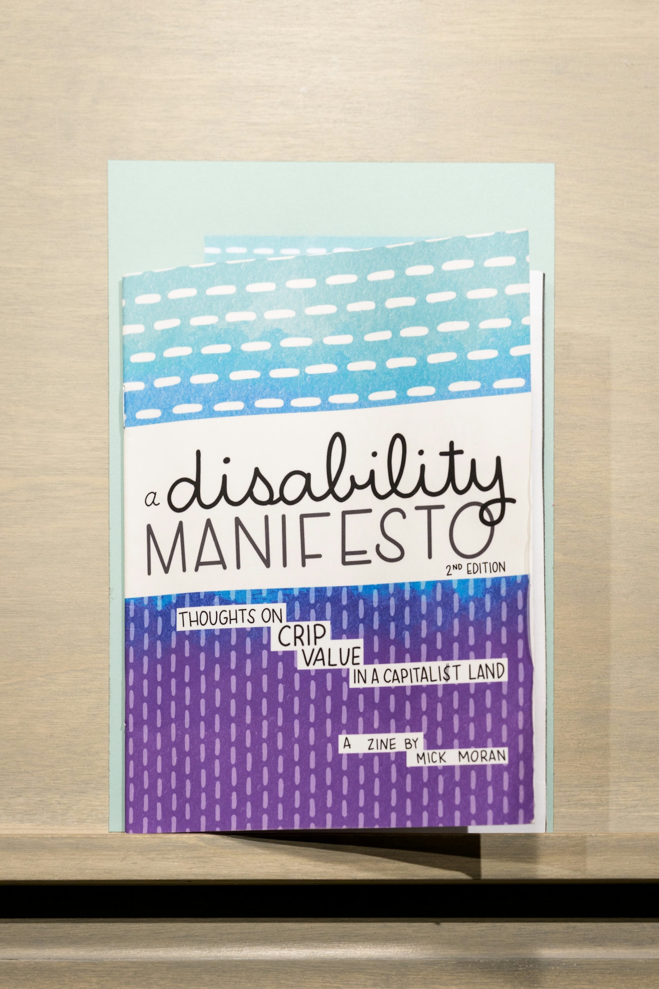 The zine 'A Disability manifesto' by Mick Moran, resting on a plinth in the gallery.