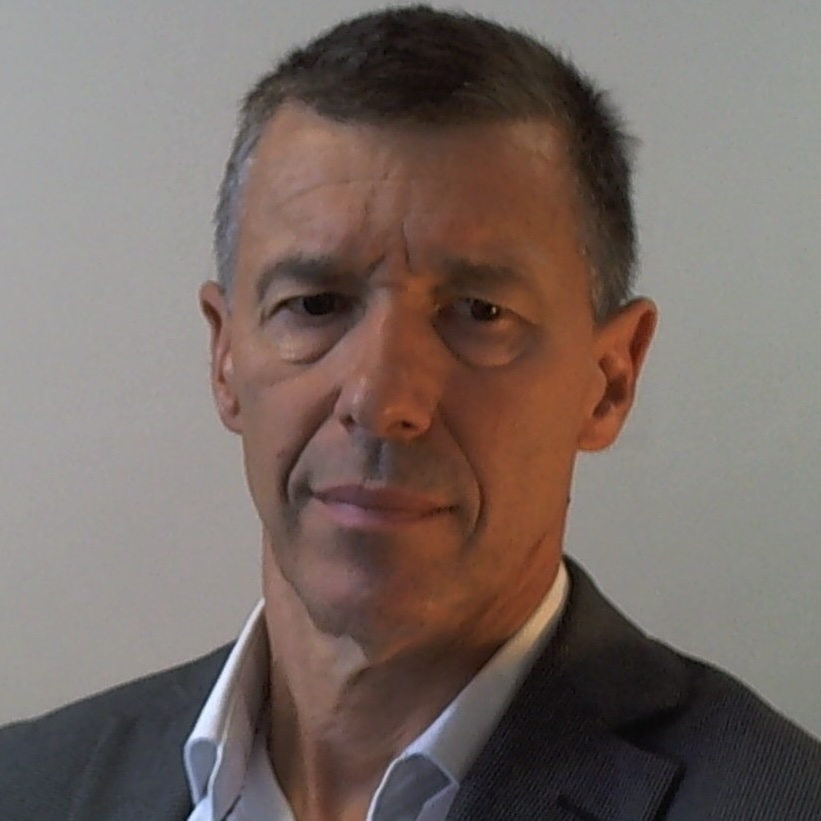Head and shoulder shot a a man with short black hair, wearing a suit jacket and shirt, no tie, and looking down and to the right.