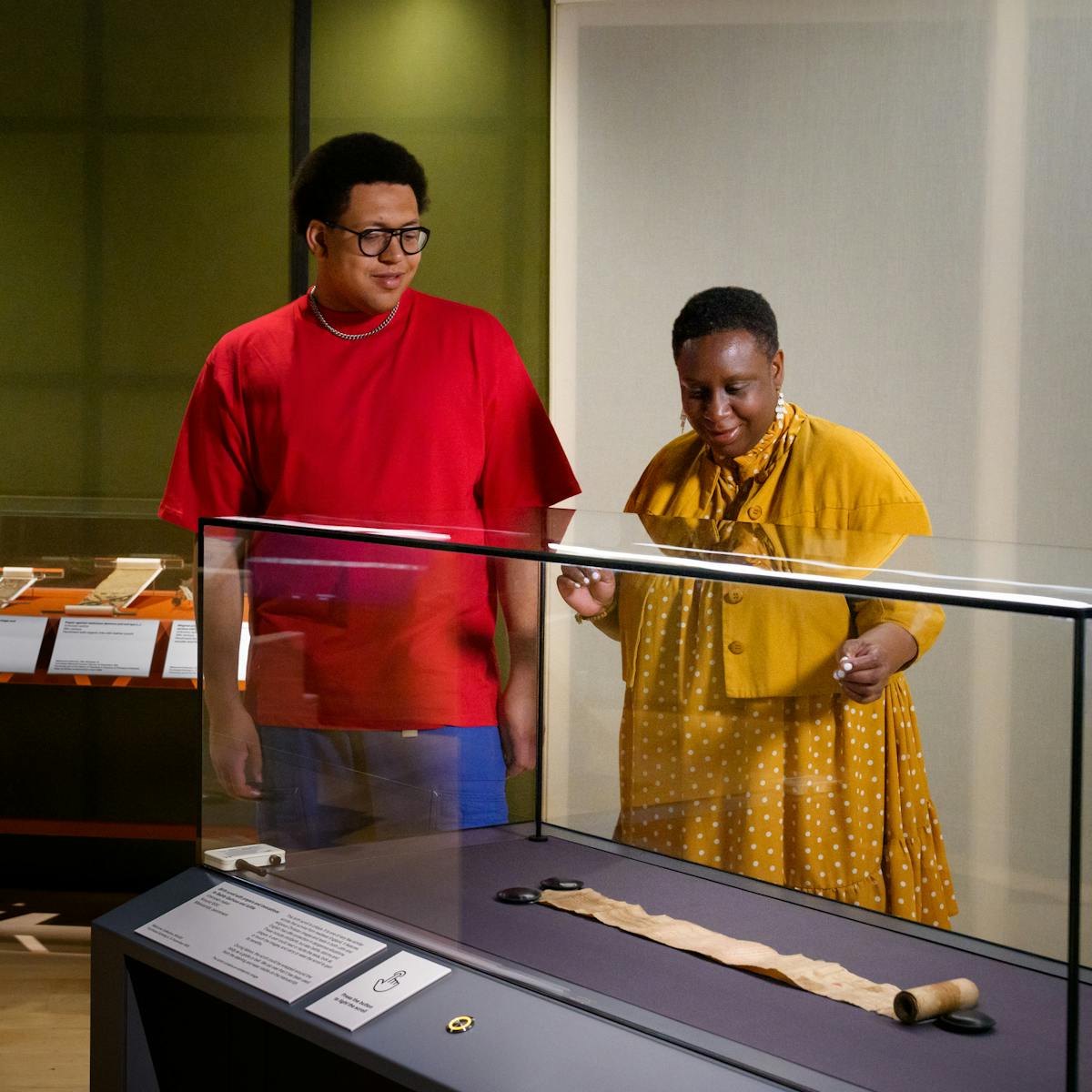 Visitors looking at scrolls, housed in glass display cases.