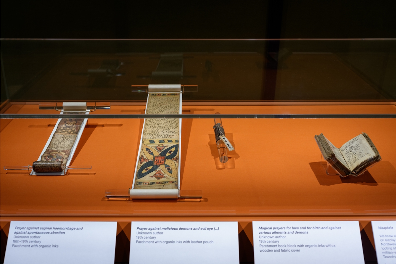 A collection of Ethiopian artefacts including scrolls and manuscripts displayed in a glass case.