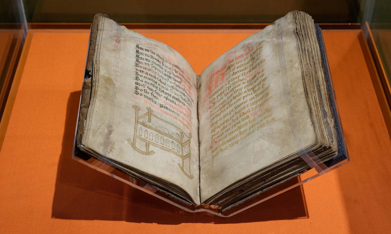 A 15th-century book on parchment, handwritten and with a drawing of a swaddled baby in a rocking cot.