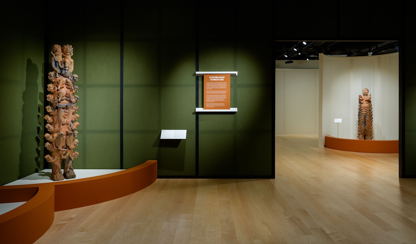 Two large terracotta scultpures of human figures on display in an exhibition gallery. They are by the Senegalese artist Seyni Awa Camara and relate to experiences of childbirth.