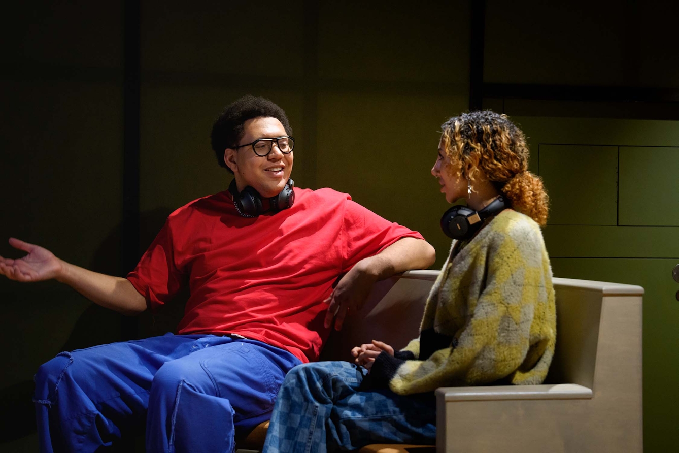 Two people sit beside each other on a bench, having an animated conversation.