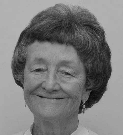 Black and white photograph of the head of a woman with short hair, who is smiling and looking at the viewer.