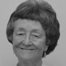 Black and white photograph of the head of a woman with short hair, who is smiling and looking at the viewer.