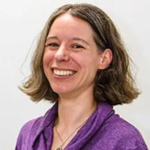 Headshot of Maria wearing a bright purple top, smiling into the camera
