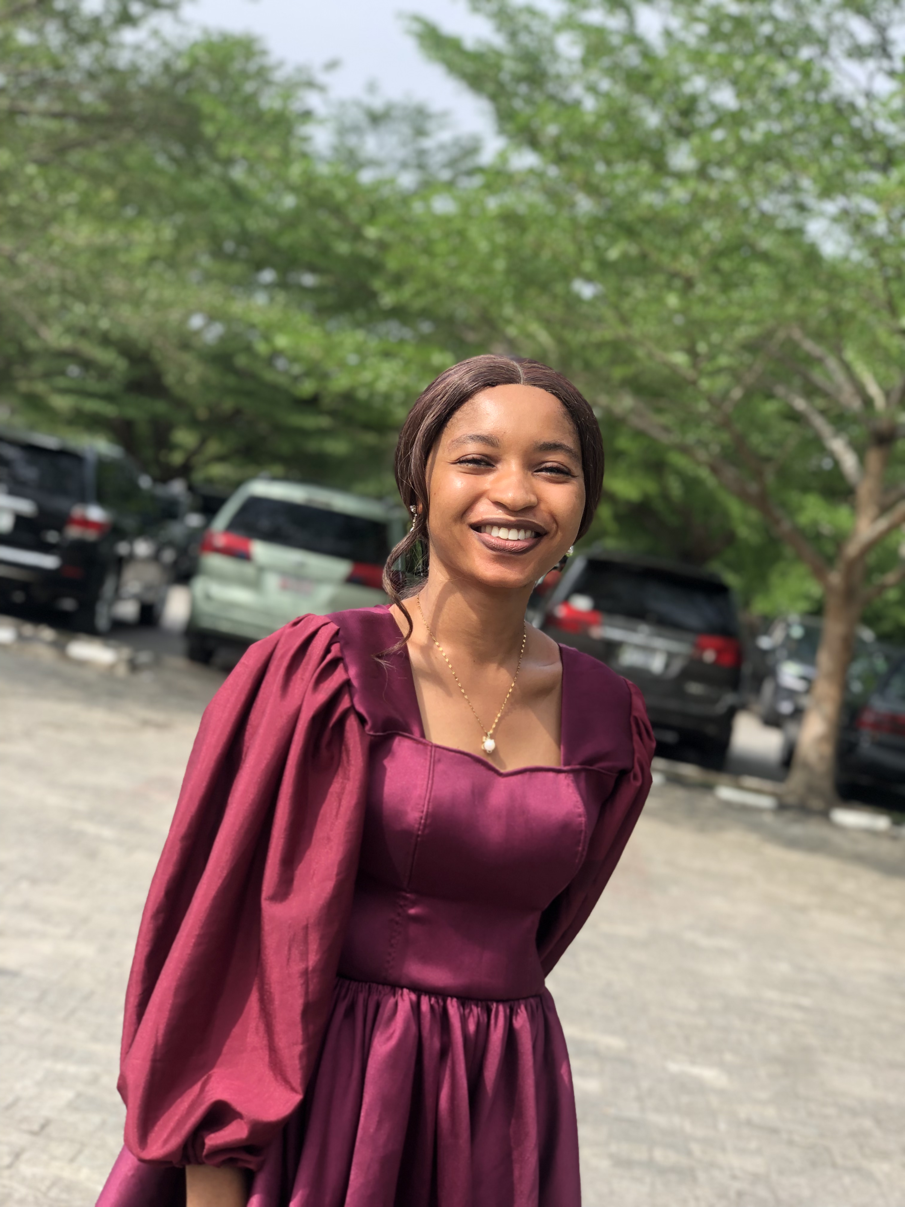 A photo of Tracy Egbele wearing a purple dress and smiling into the camera