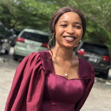 A photo of Tracy Egbele wearing a purple dress and smiling into the camera