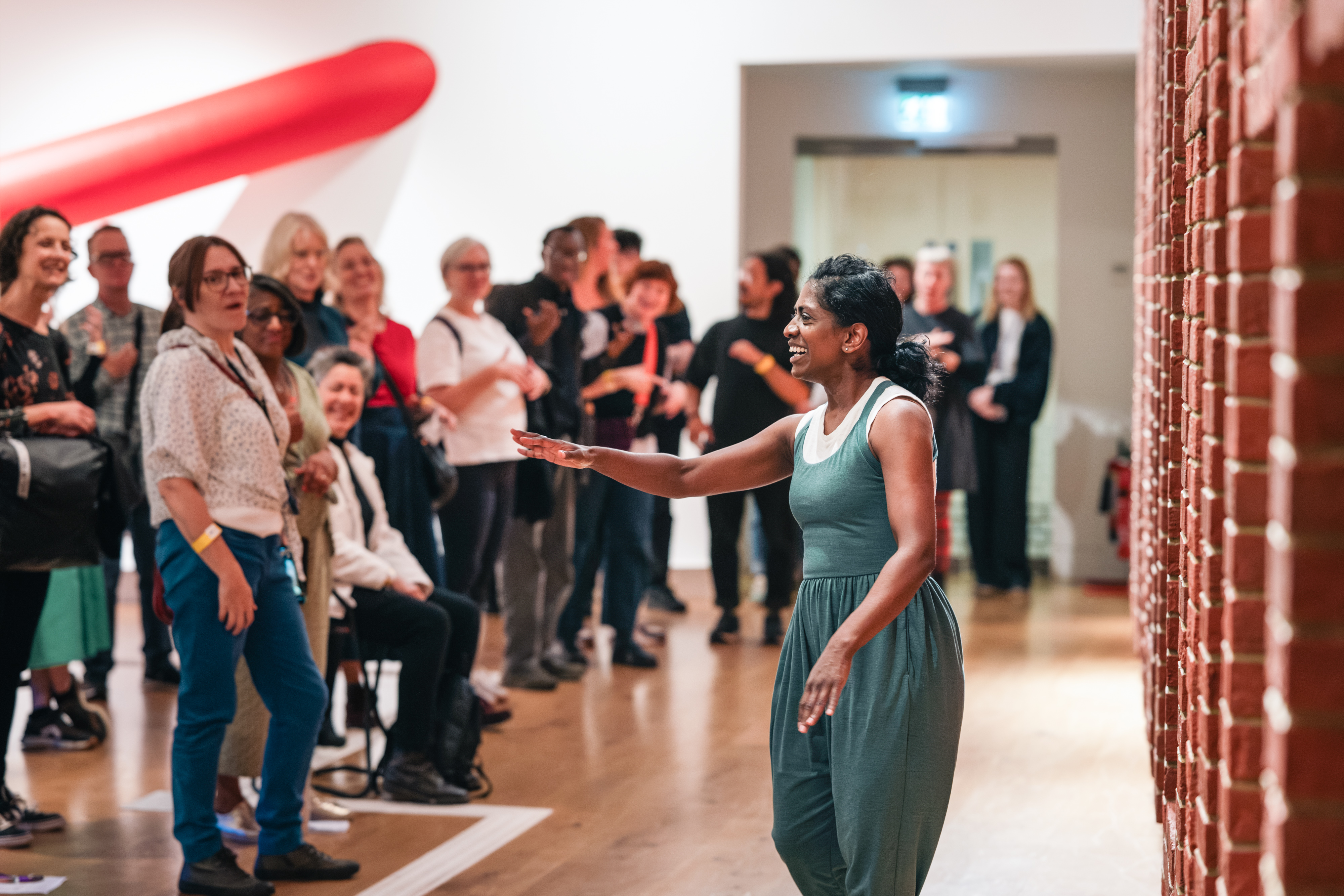 An audience engaging with a performer using BSL in a gallery space.