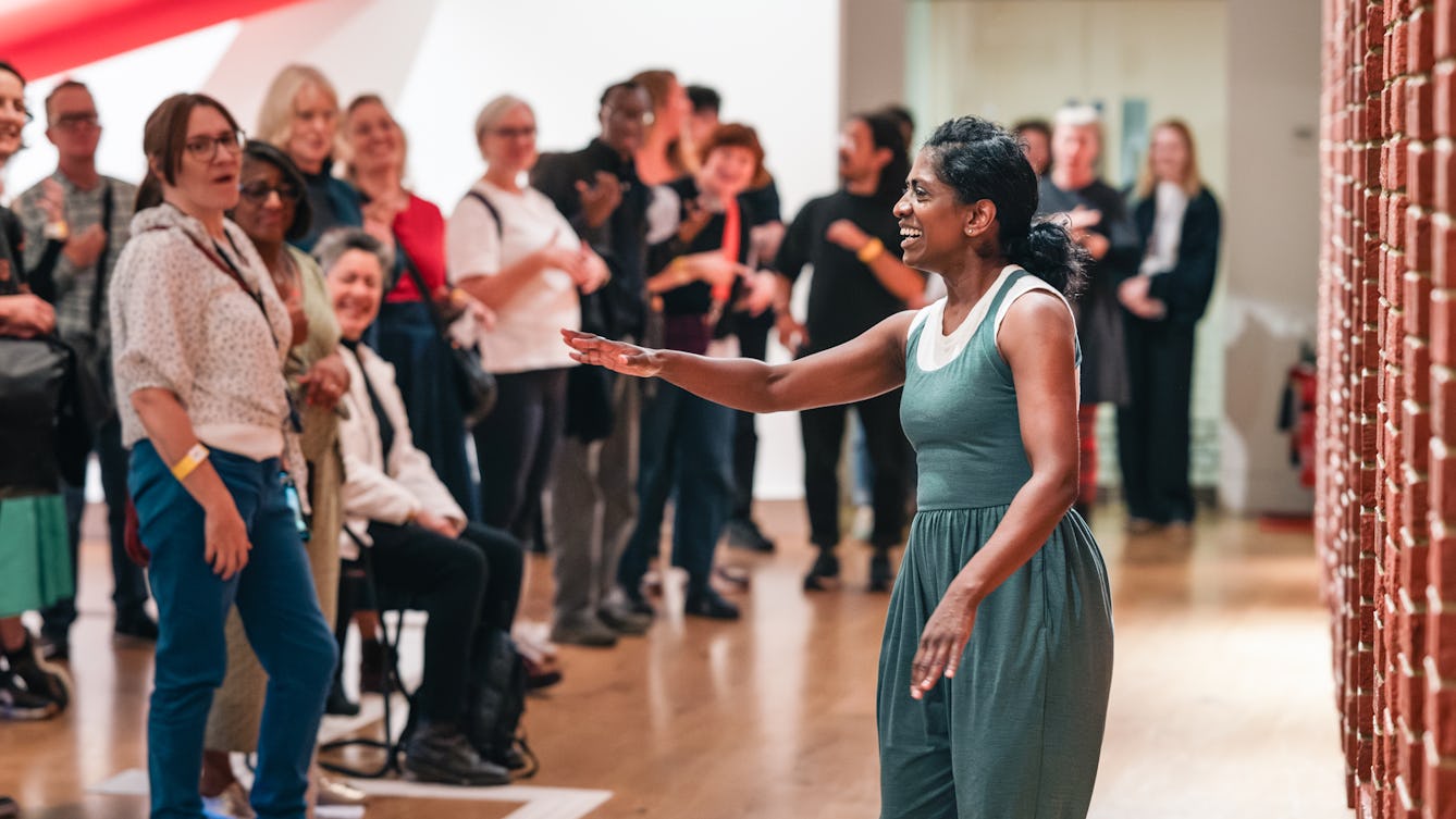An audience engaging with a performer using BSL in a gallery space.