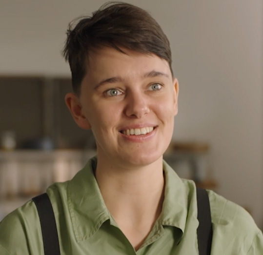 Head and shoulders photo of a young person with short dark hair. They are smiling and facing the viewer but looking to the right of the image.