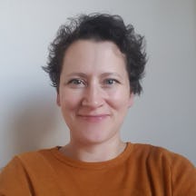Black and white photograph of a the head and shoulders of a young woman with short dark hair. She is smiling and looking directly at the camera.
