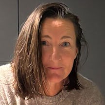 Photograph of the head and shoulders of a woman with dark shoulder-length hair. She is smiling and looking at the camera.