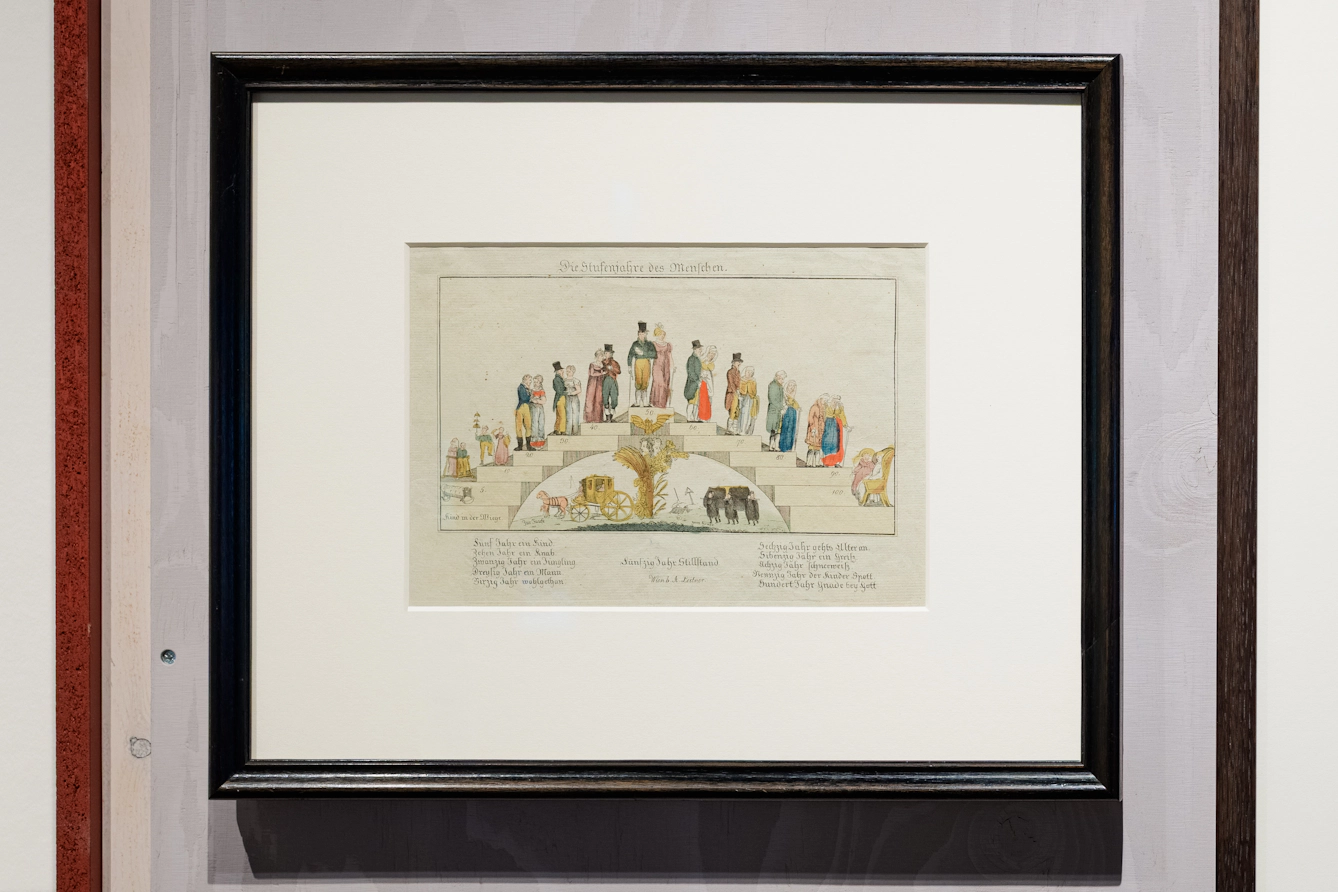 A series of steps arc in the shape of a bridge. A couple ascends the steps and grow in age as they do, reaching peak health and vitality at the top of the bridge. As they descend their ageing continues until they are old and frail.