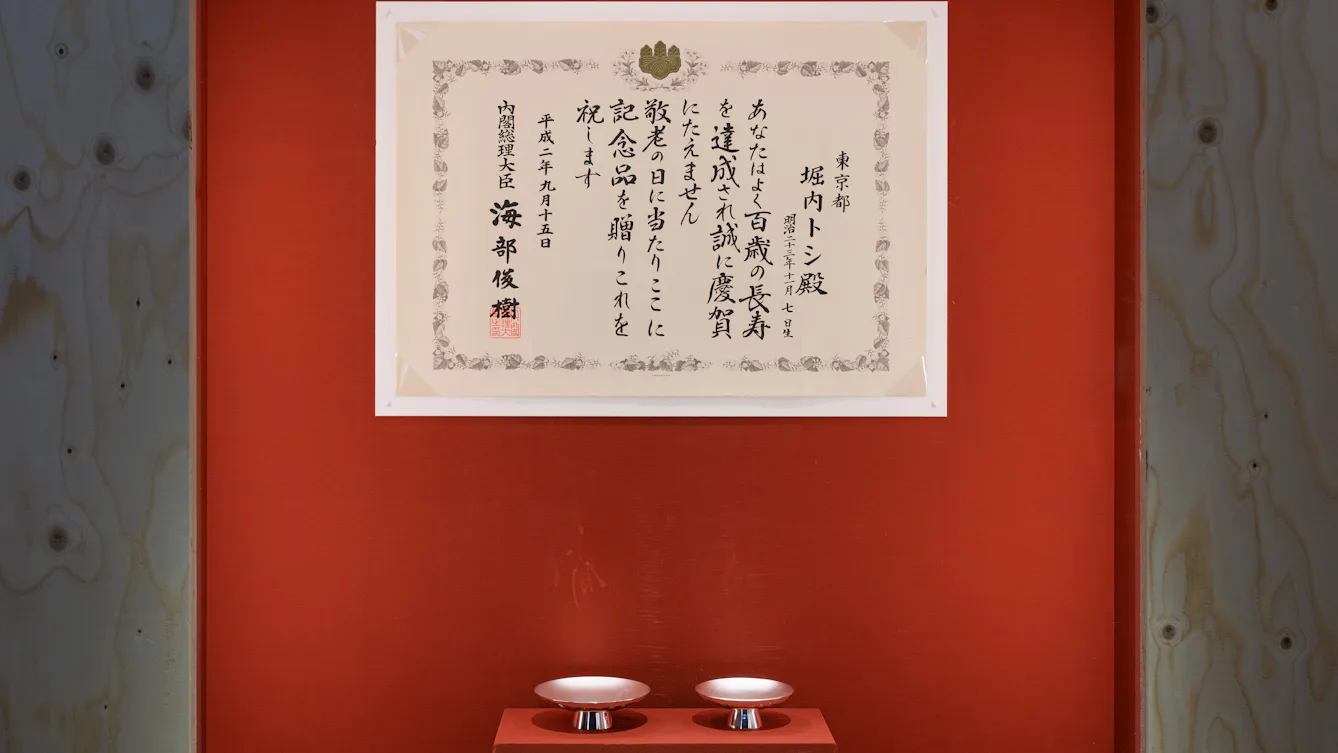 A framed Japanese centenarian certificate congratulating someone on reaching 100 years of age.