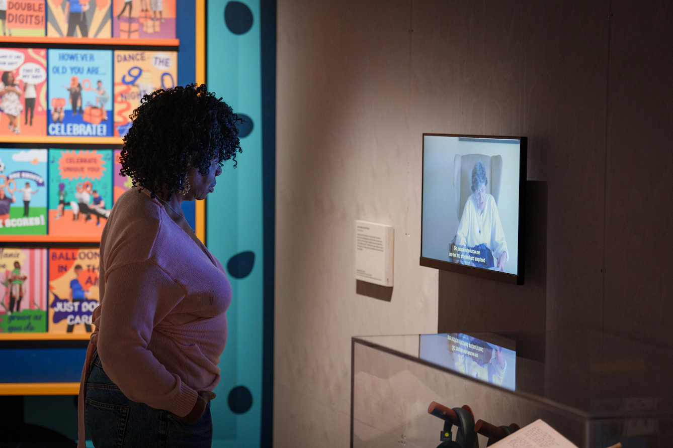 A visitor looks at a screen where a poet is reading.
