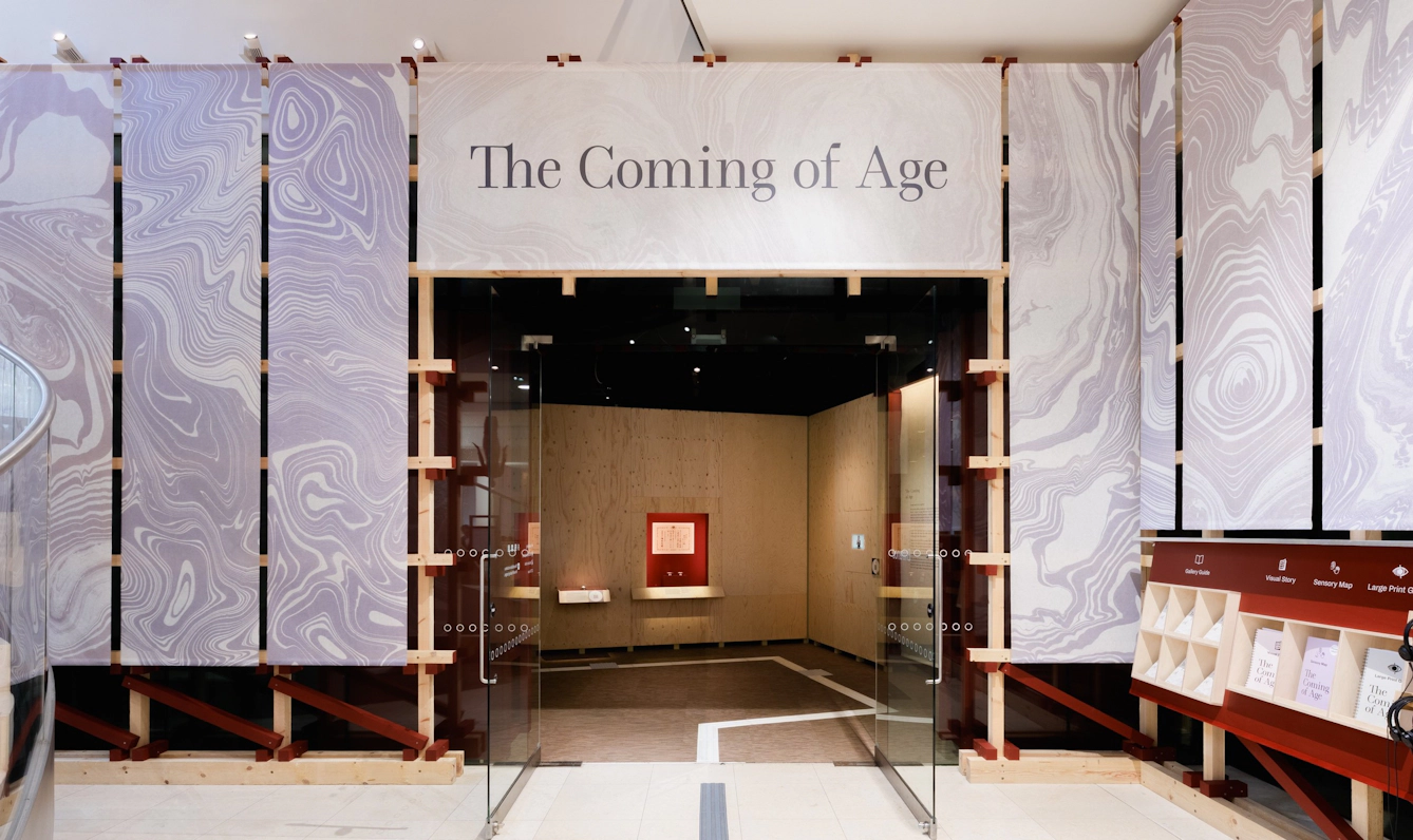 The atrium outside Gallery 1 at Wellcome Collection featuring a large sign above the doorway that reads 'The Coming of Age'.