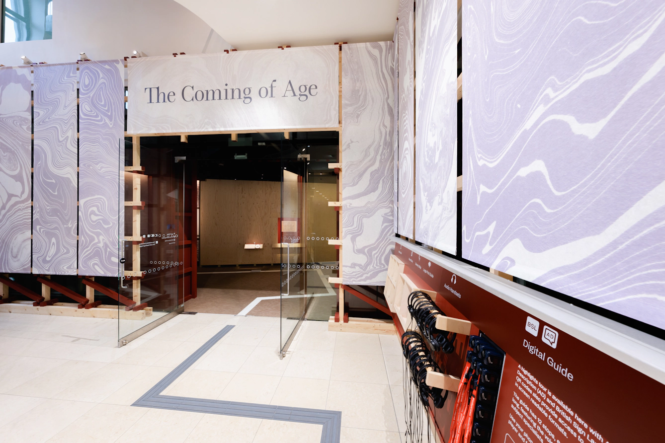 The atrium outside Gallery 1 at Wellcome Collection featuring a large sign above the doorway that reads 'The Coming of Age'.