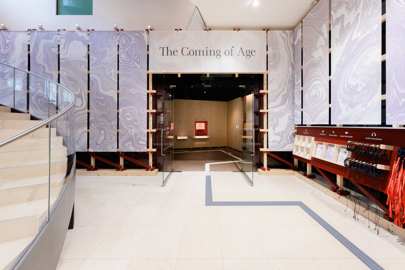 The atrium outside Gallery 1 at Wellcome Collection featuring a large sign above the doorway that reads 'The Coming of Age'.