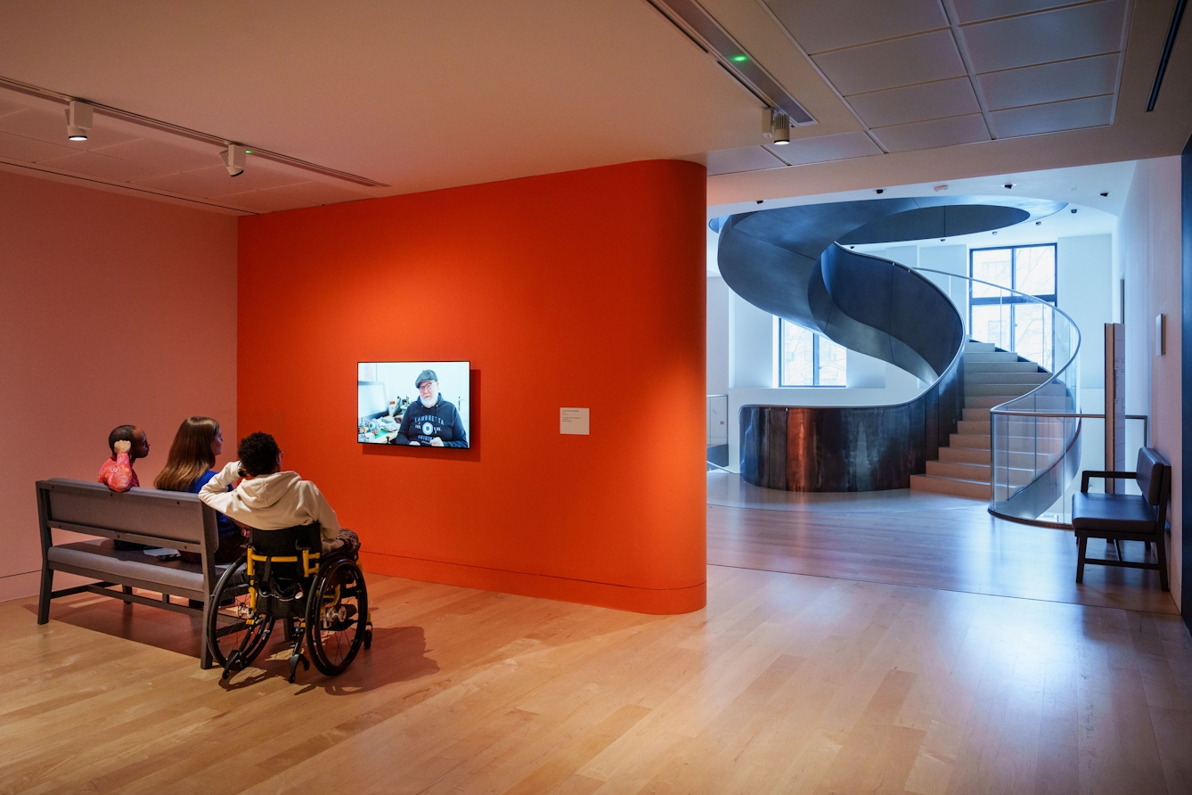 Photograph of people watching a video in the lobby area outside the entrance to Gallery 2.