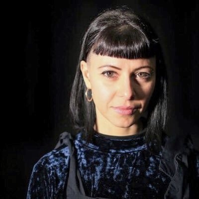 Headshot of Jess Mabel Jones in front of black background.