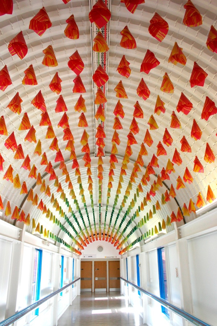 Individual red, green and yellow plastic cones hang from the ceiling in a hospital corridor.