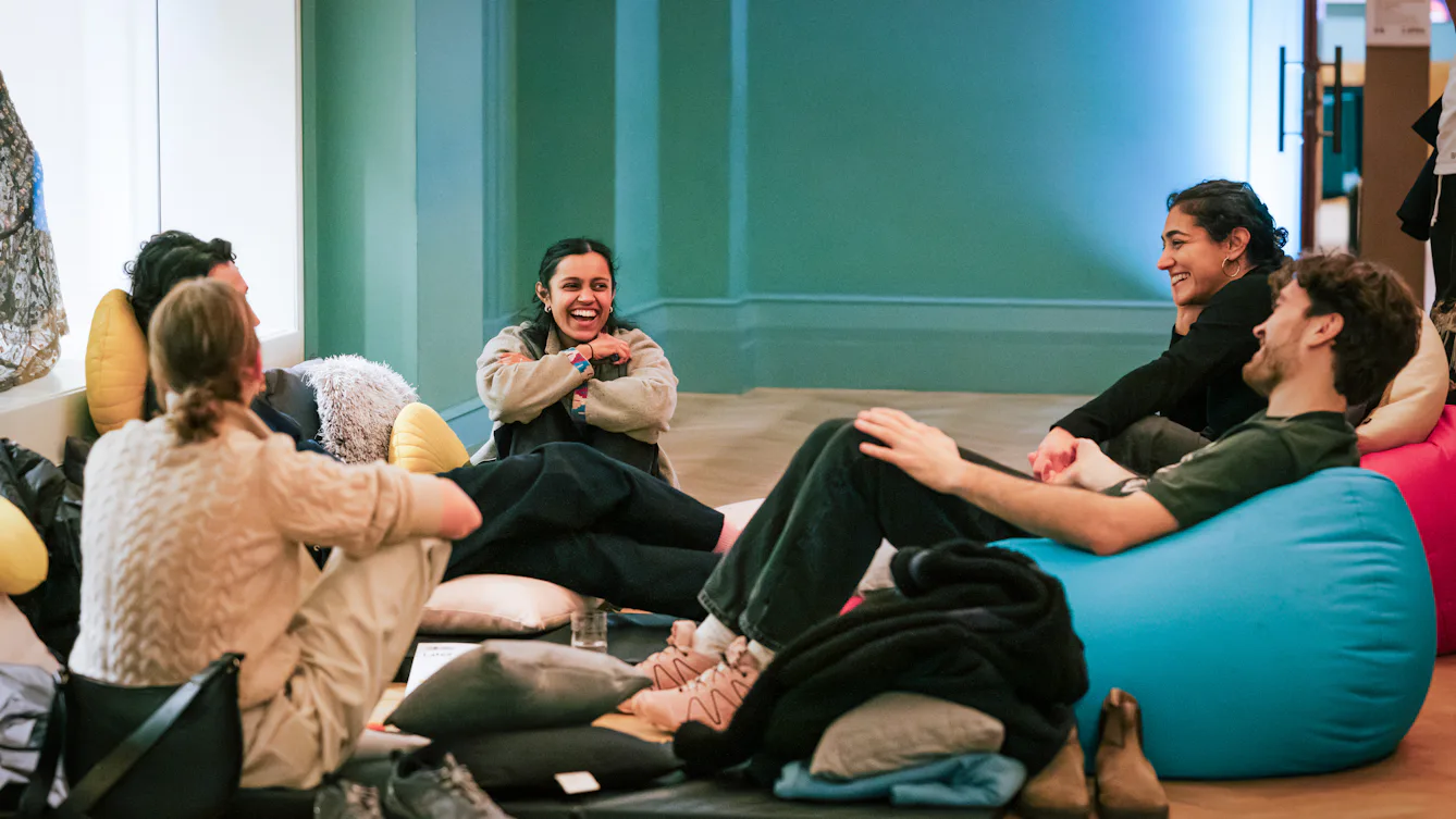 A group of people sat casually on beanbags, having a conversation and smiling.