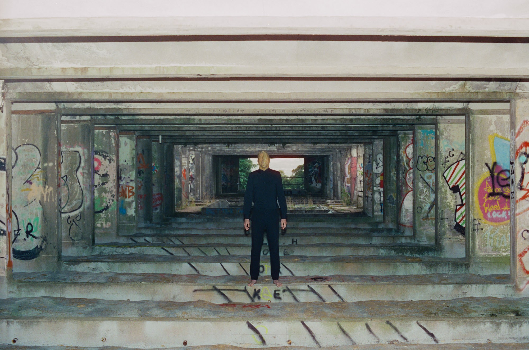 Photo of a person wearing black standing in a concrete structure.