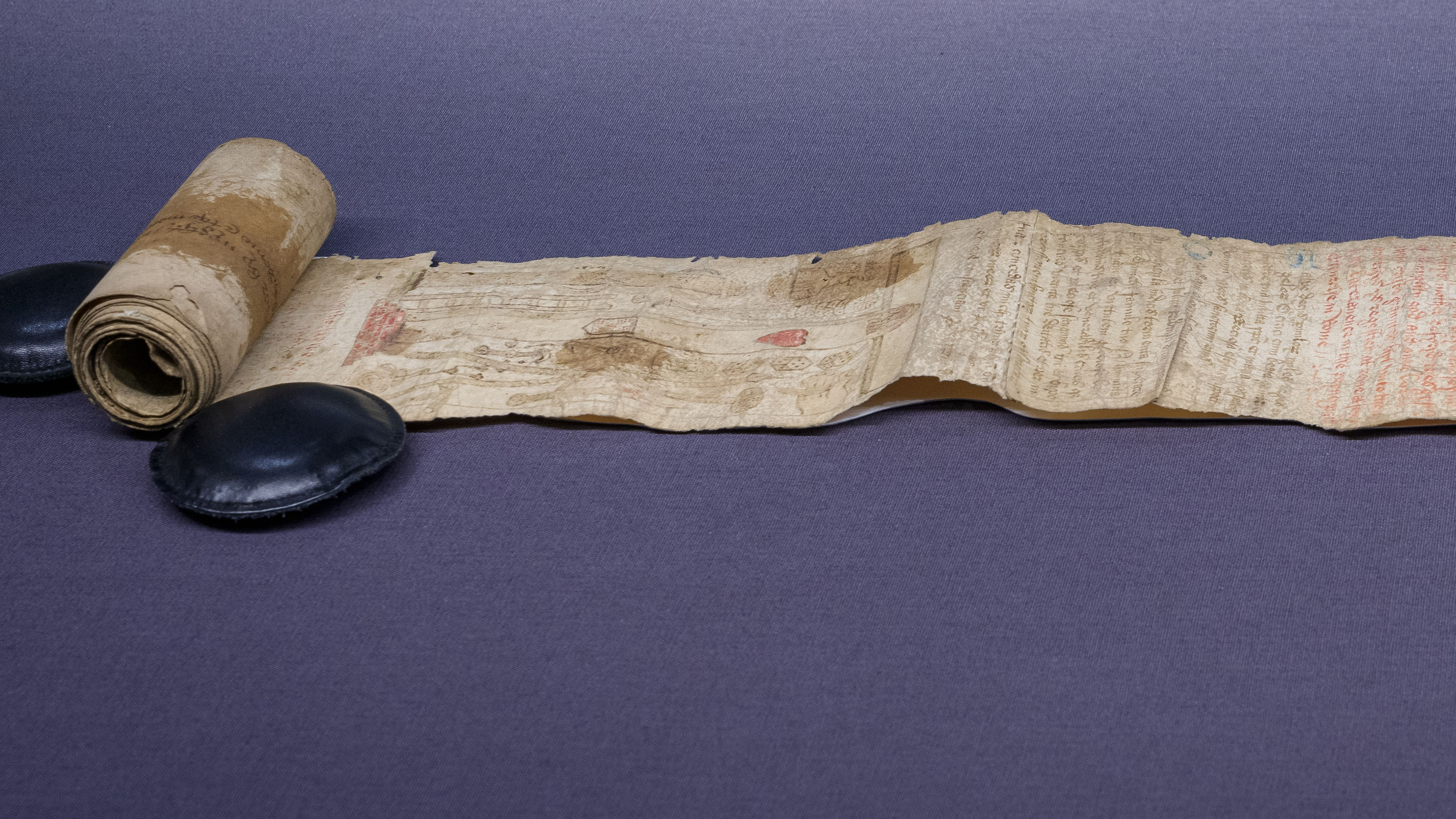 A partially unrolled parchment scroll with faded text, images and stains on its surface, from c1500 CE. Featured in an exhibition at Wellcome Collection: 'Expecting: Birth, Belief and Protection', 24 October 2025 – 19 April 2026.