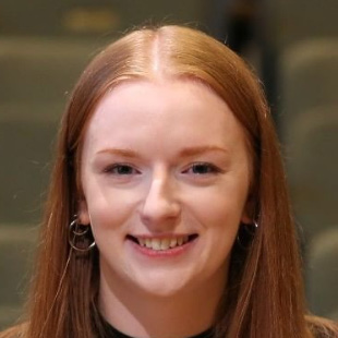 Black and white photograph of a young woman with long straight hair. She is smiling and looking directly at the camera.