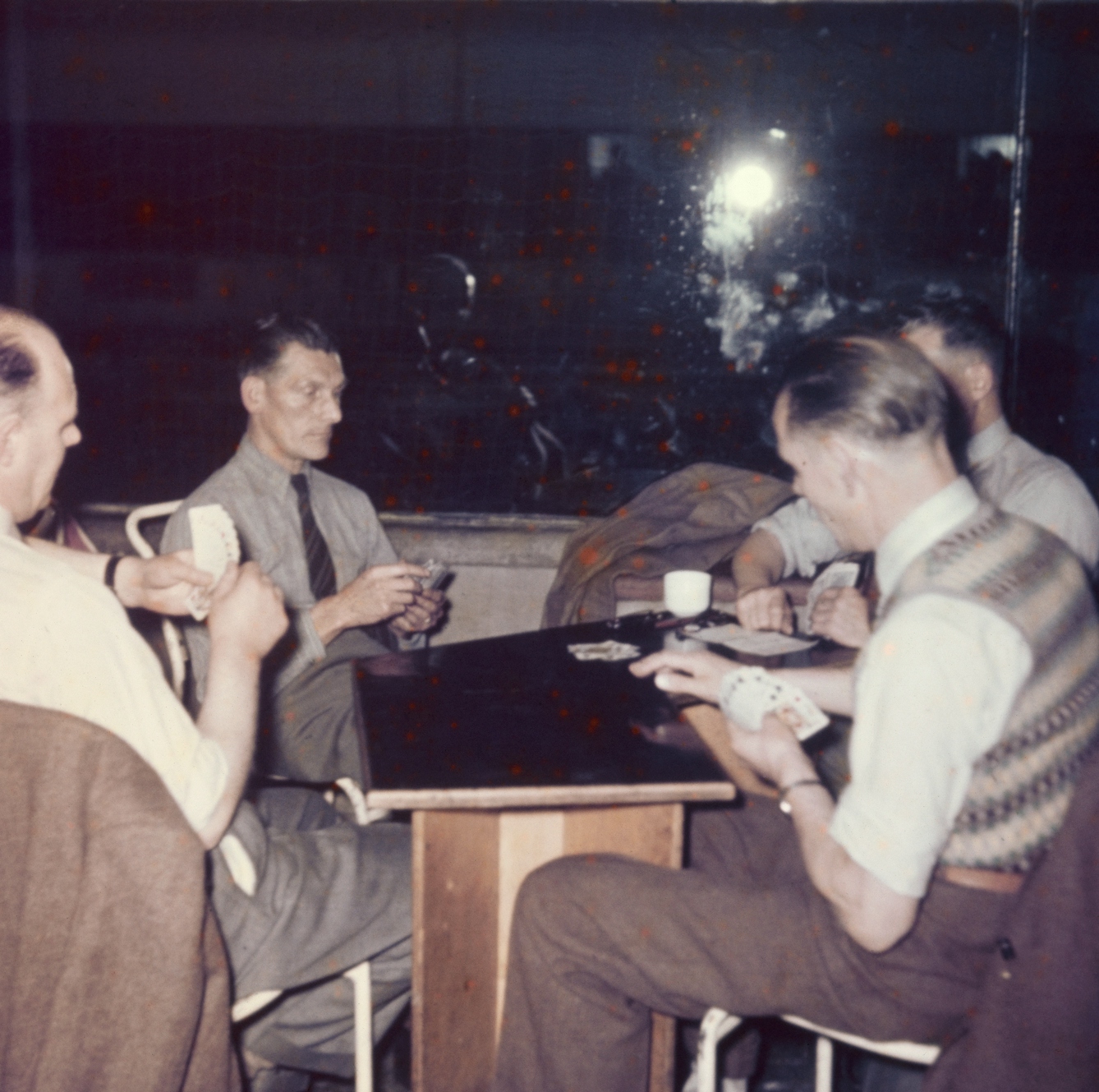 Photograph from the mid-20th Century Peckham Pioneer Centre, showing four men seated at a table with playing cards in their hands. 