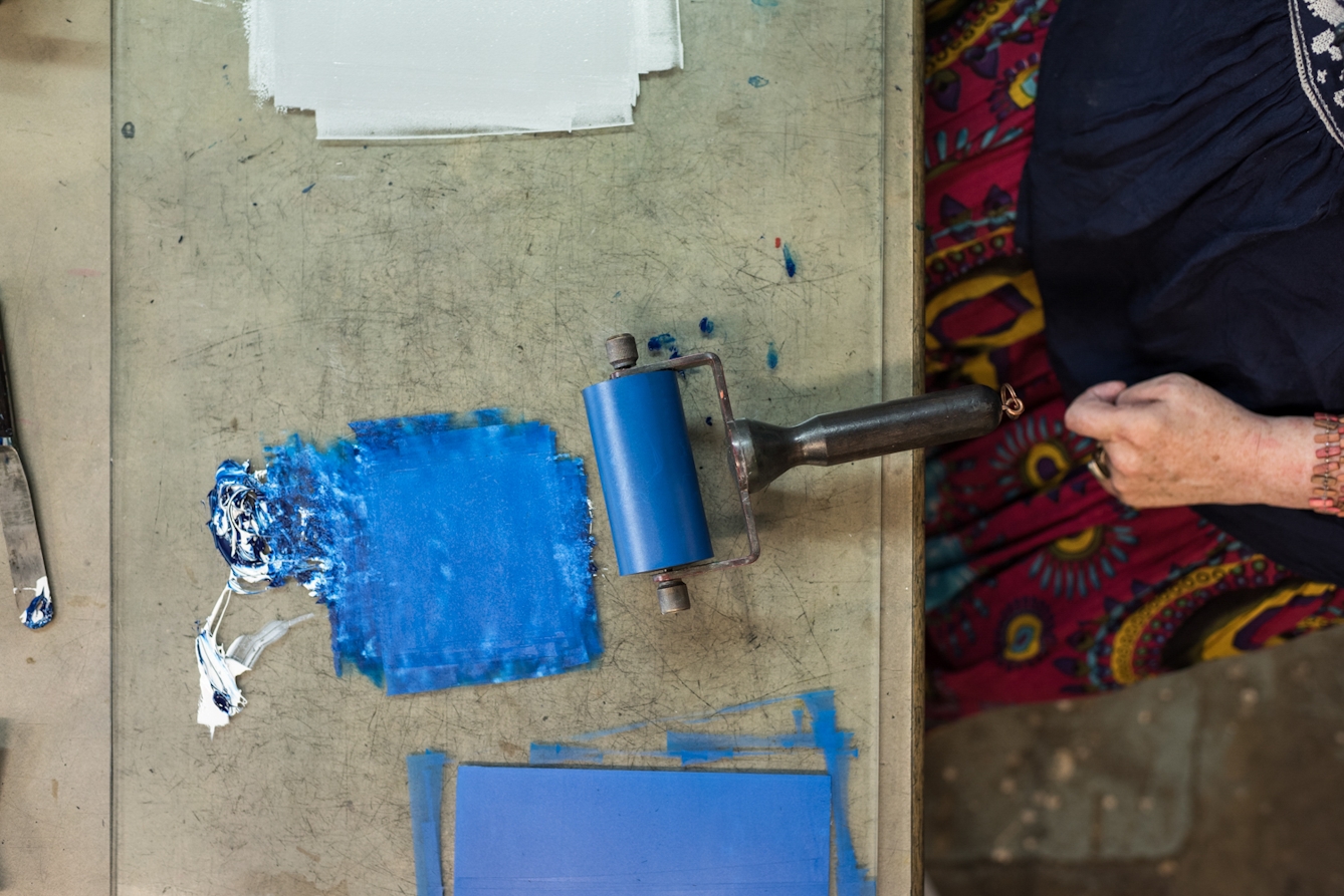 Photograph of the hand of a woman about to use a print roller to create an artwork.
