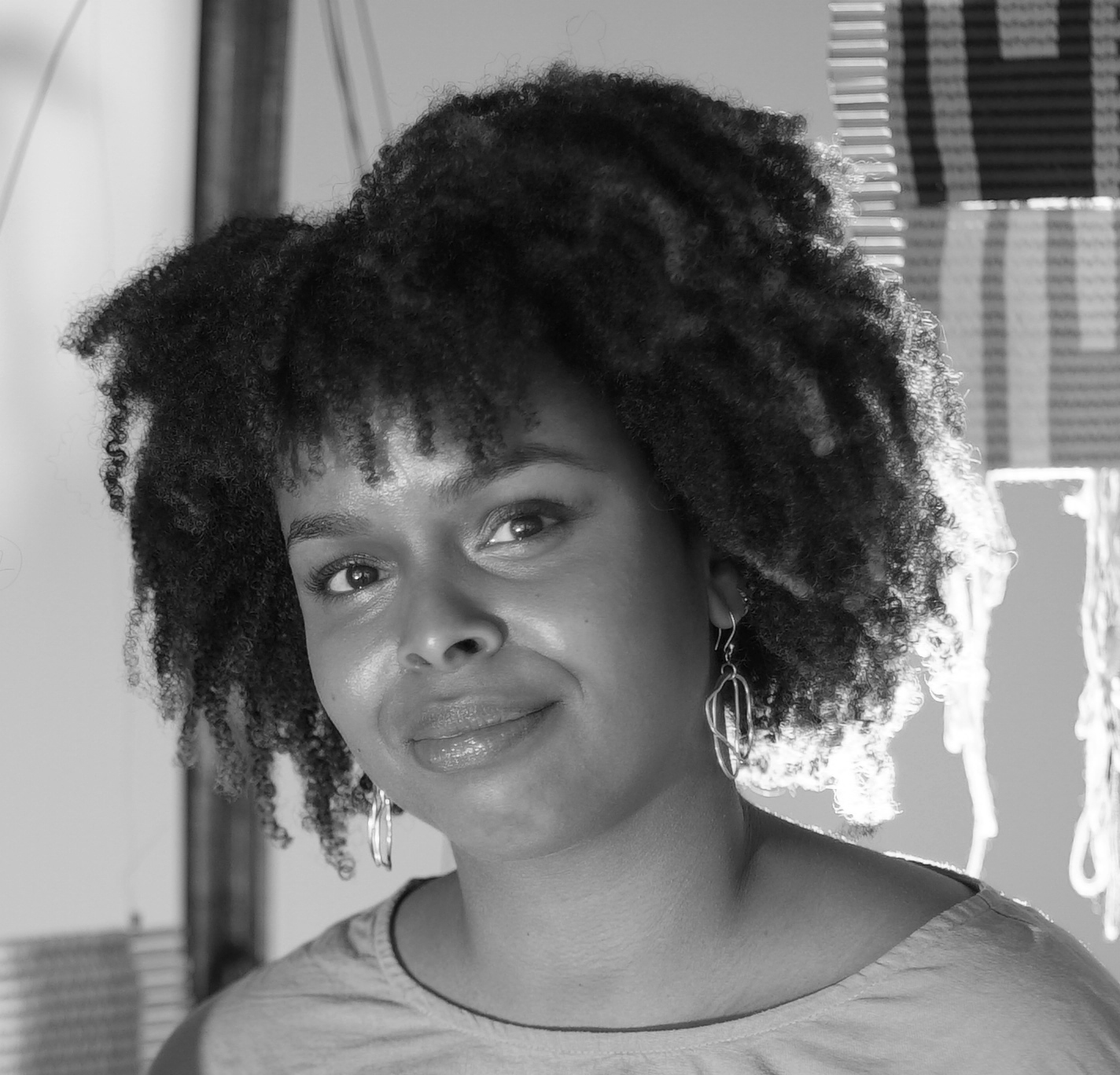 Black and white photograph of the head and shoulders of a young Black woman smiling and looking straight at the camera.