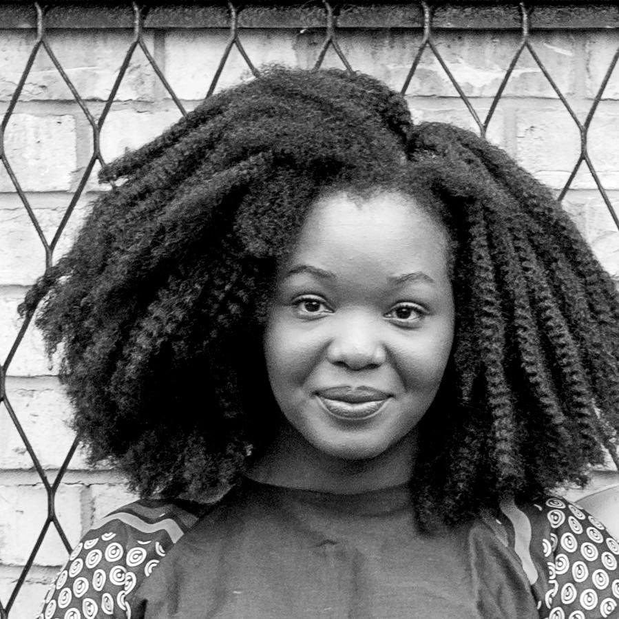 Black and white photograph of a young black woman with a shoulder-length afro hairstyle. Teh woman is smiing and looking straight at the camera.