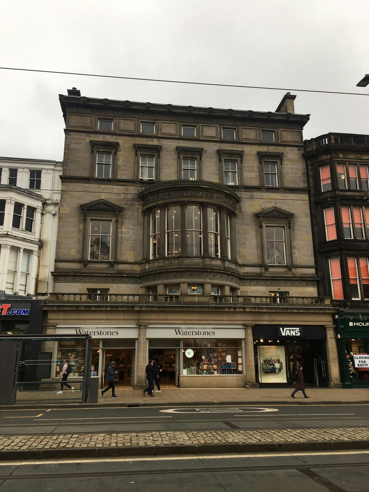Colour photograph of the site of the Fire Island nightclub in Edinburgh. It is a stone building with a prominent round central window on the first floor. Below are now a Waterstones store and a Vans store. 