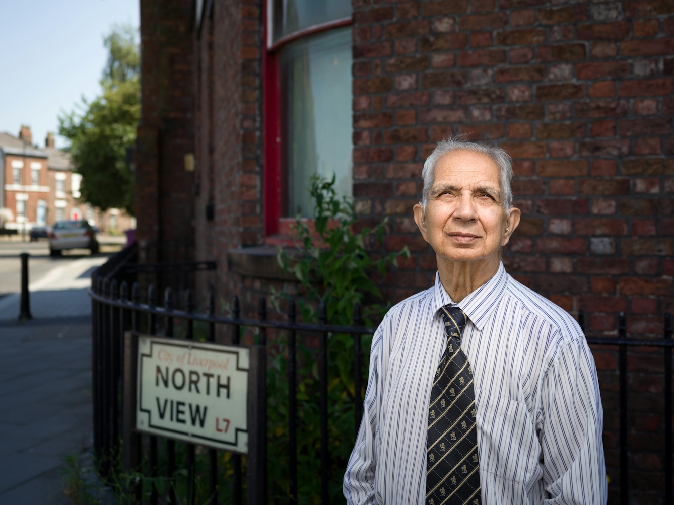 Photographic portrait of Dr Shiv Pande outside his former GP surgery. 