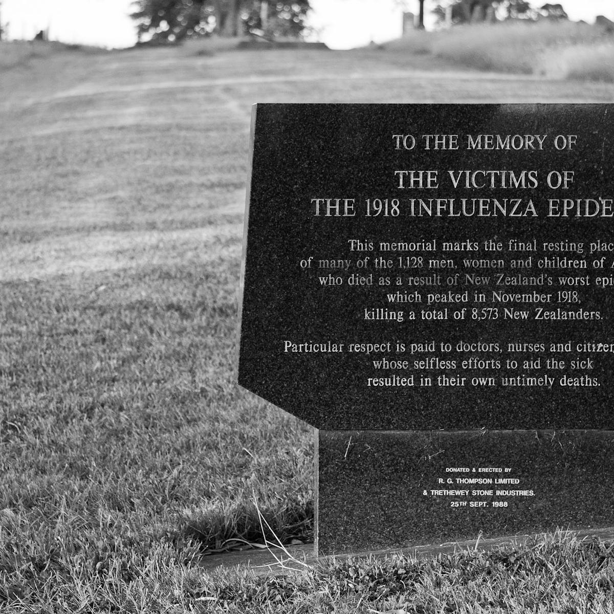Plaque reads: This memorial marks the final resting place of many of the 1,128 men, women and children of Auckland who died as a result of New Zealand's worst epidemic which peaked in November 1918, killing a total of 8,573 New Zealanders. At the bottom it says it was donated and erected in 1988.