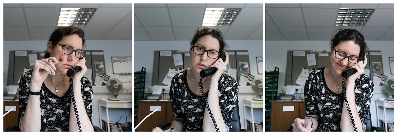 Photographic triptych showing the same woman in each image, sat in an office environment. In the left hand image the woman holds a landline telephone receiver to her left ear, her right hand is raised holding a pen against her cheek. She is looking off to camera right camera. In the middle image she holds the receiver to her left ear and she is looking straight towards the camera. In the right hand image she holds the receiver to her left ear with her right hand and she is looking down to the desk smiling.