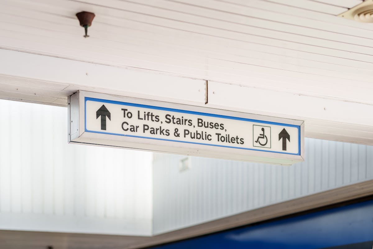 A photograph of a sign with arrows and text that reads to lifts, stairs, buses, car parks and public toilets.