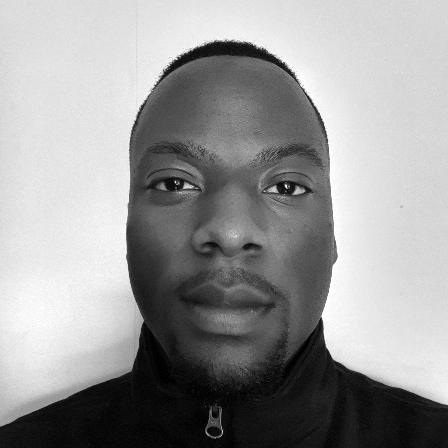 Heed and shoulders photograph of a man with short hair and a short beard wearing a fleece jacket zipped up to the neck.  