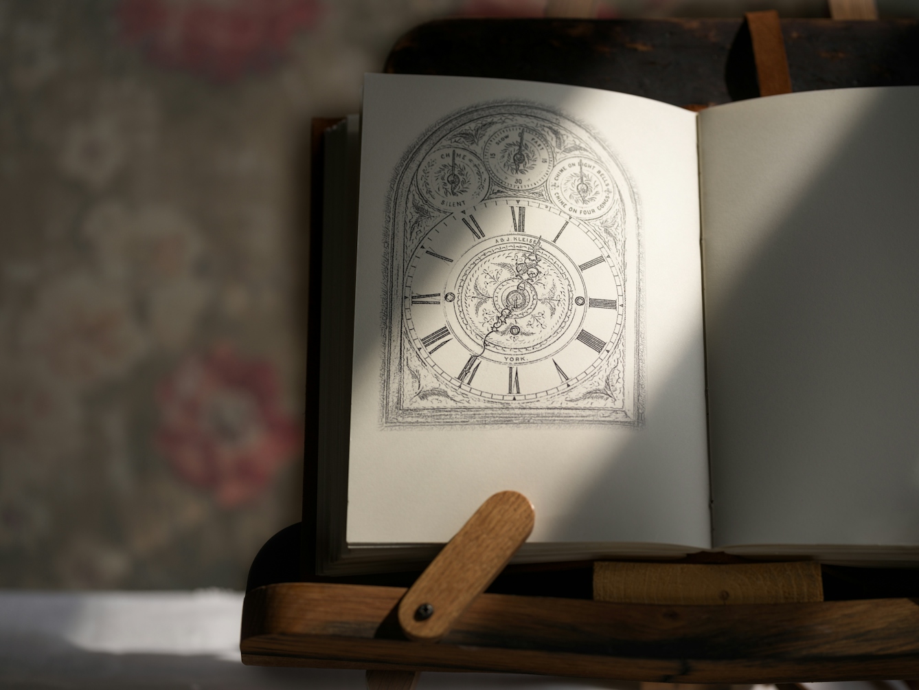 Photograph of a notebook on a wooden book stand, lit by a window from the right, casting a shadow on half of the page. On the left page there is a sketch of a clock.